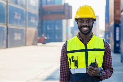 Docker en gilet fluorescent et casque, sur un terminal à conteneurs